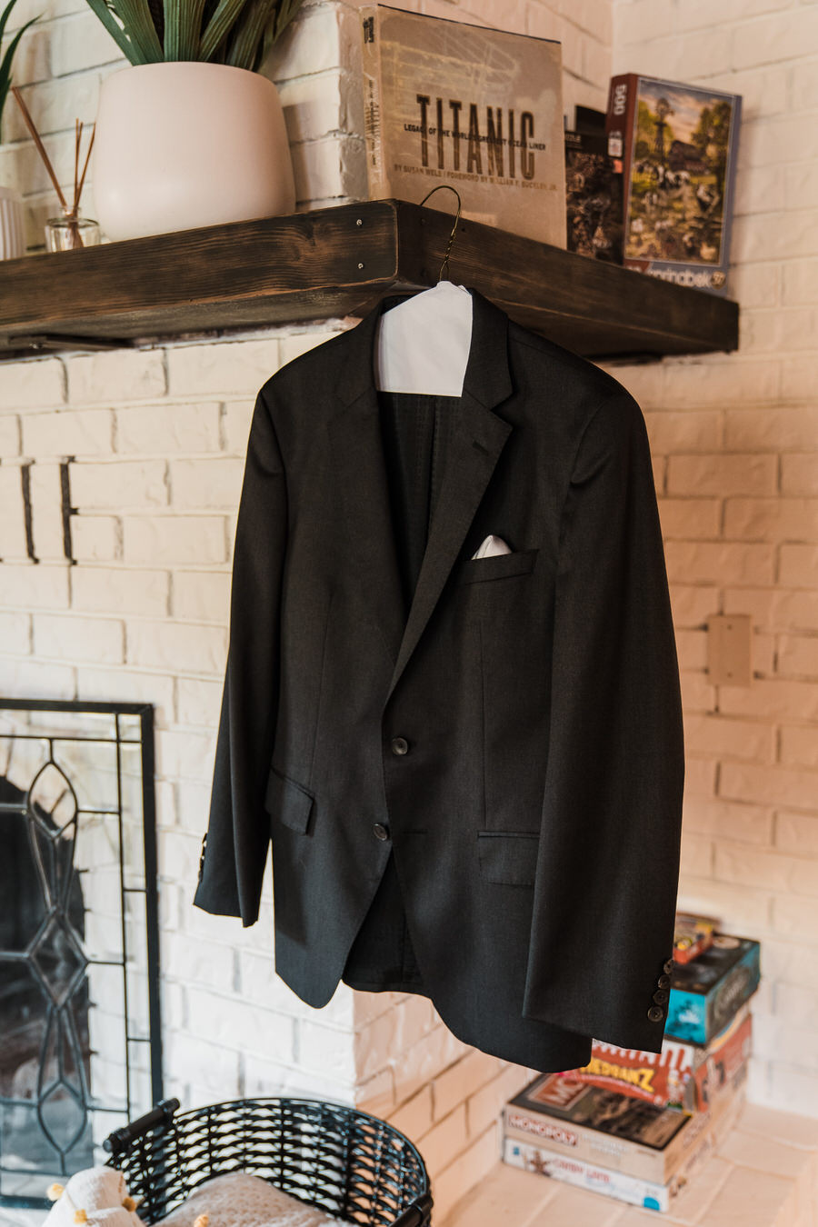 A groom's suit jacket hanging on a fireplace mantle
