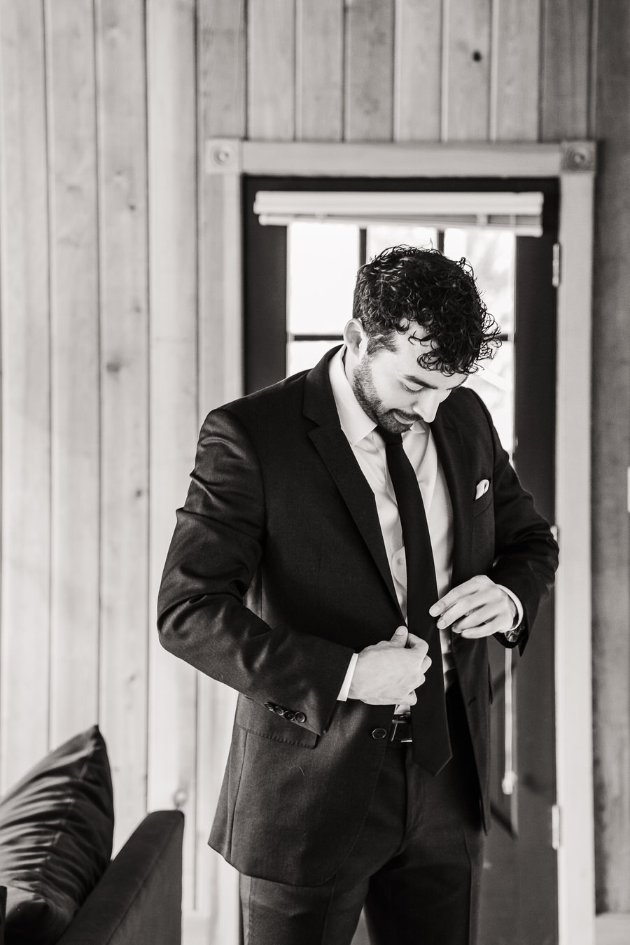 A groom buttons his jacket on his wedding day