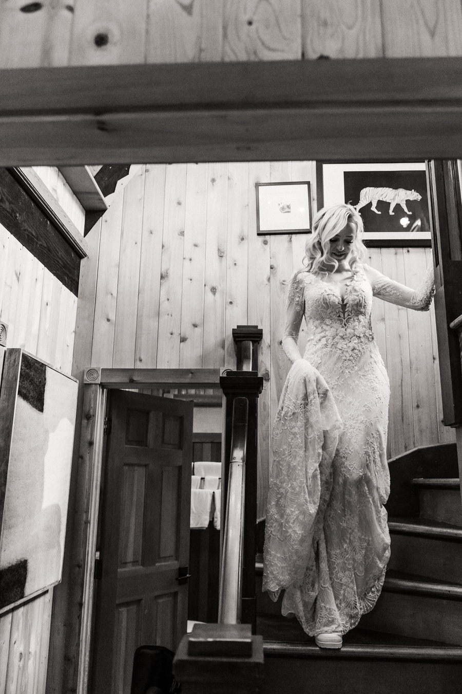 A bride walks down the steep stairs of a lakefront cabin