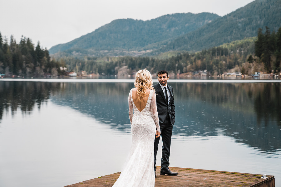 A bride and groom share their first look together on a dock on Lake Sutherland