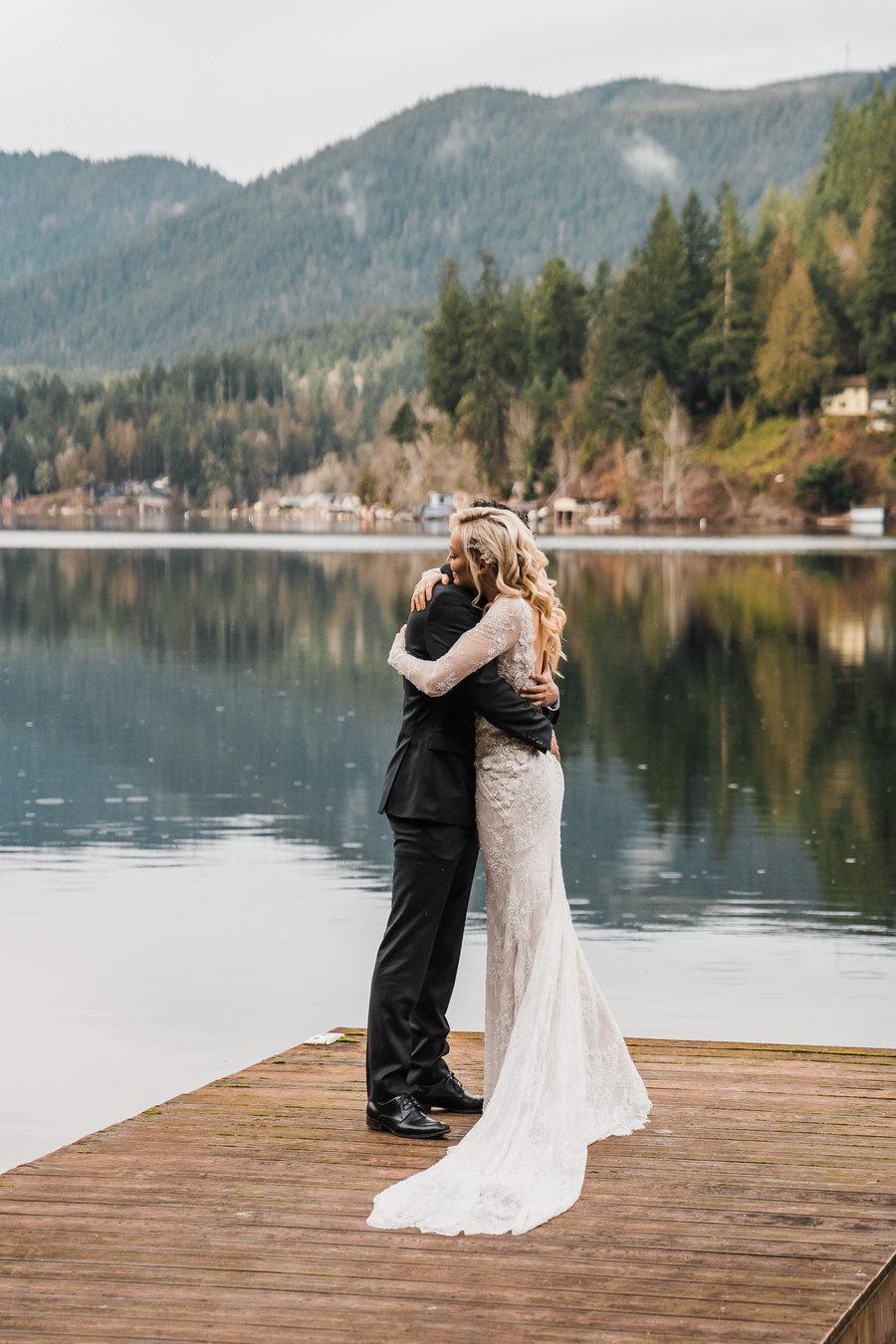 A bride and groom hug while standing on a dock on Lake Sutherland