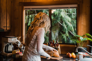 A bride makes peanut butter and jelly sandwiches while wearing her wedding dress