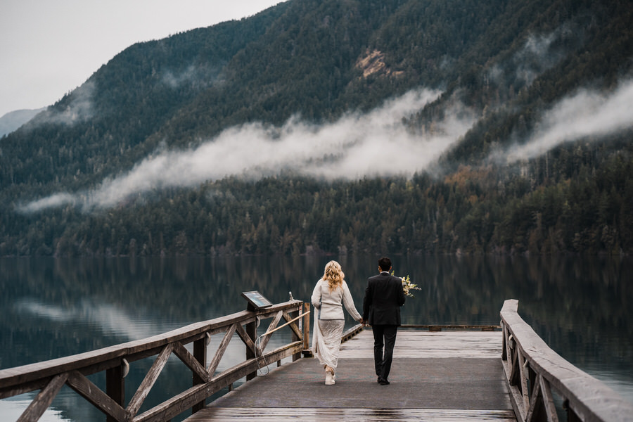 A bride and groom walk out to the end of the dock on Lake Crescent to say their wedding vows