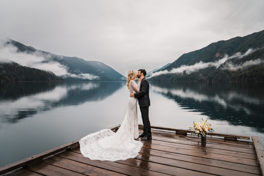 A bride and groom share their first kiss after their wedding ceremony on the dock at Lake Crescent in Olympic National Park