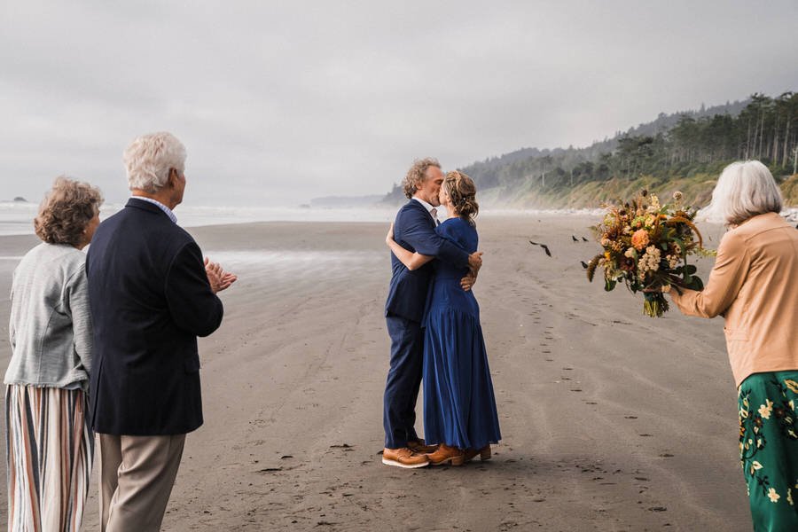 A bride and groom share their first kiss on Kalaloch Beach after their small elopement ceremony