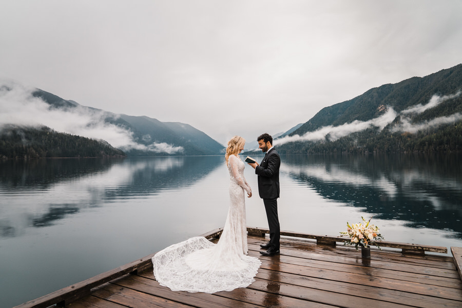 A groom says his vows to his bride while standing on a dock on Lake Crescent in Washington
